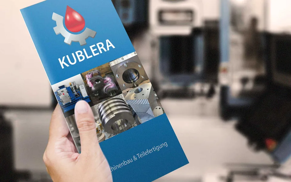 Flyer von Kublera Maschinenbau in einer Hand, im Hintergrund die Werkhalle